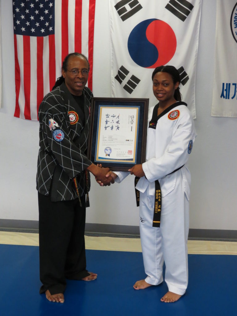 Master Bell shaking hands with student while holding award